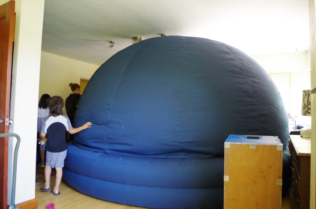 Blue portable planetarium inflating in living room